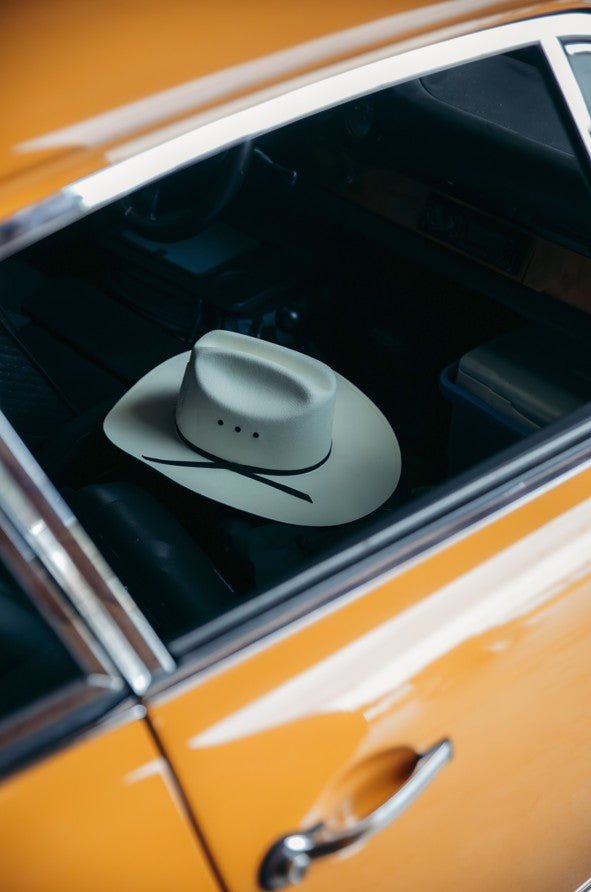 Cowboy hat decal on a car window with an orange vehicle exterior framed
